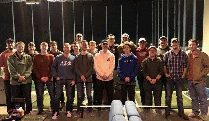 Members of Lambda Sigma Phi pose for a photo together at Top Golf
